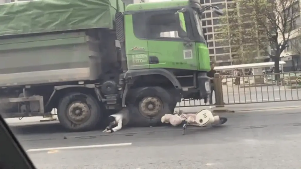 Người phụ nữ đi xe máy chui ra từ gầm xe ben